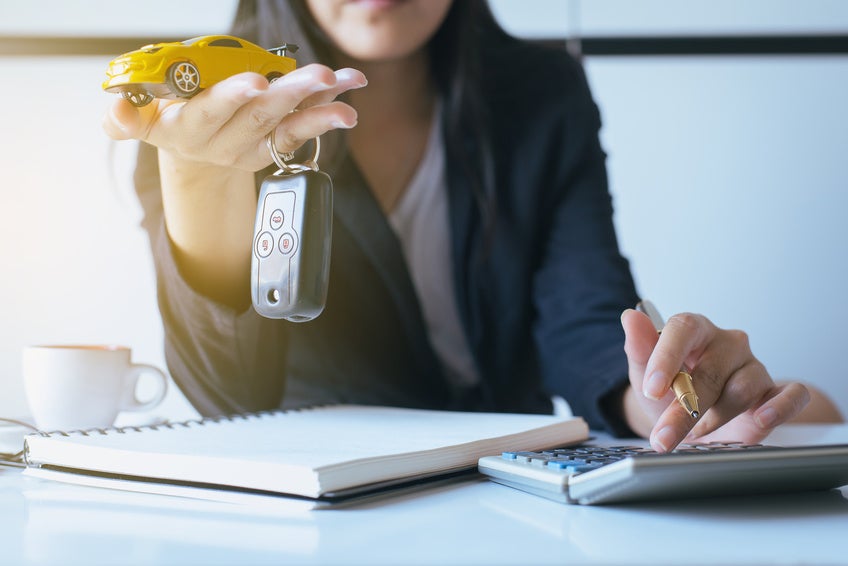 Mazda Financial Service expert holds yellow toy car while making calculations.