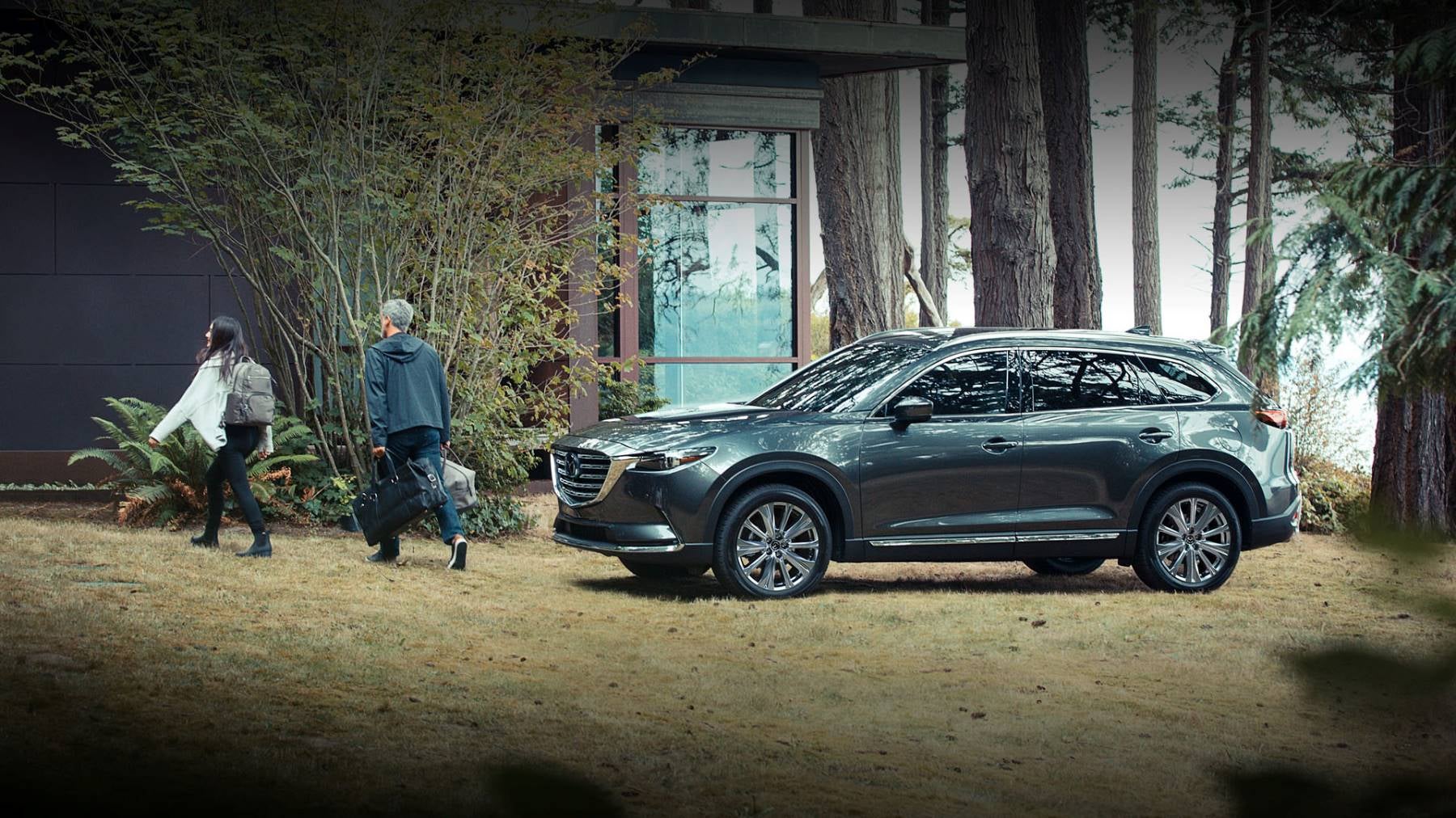 Family walking from their green 2023 Mazda CX-9.